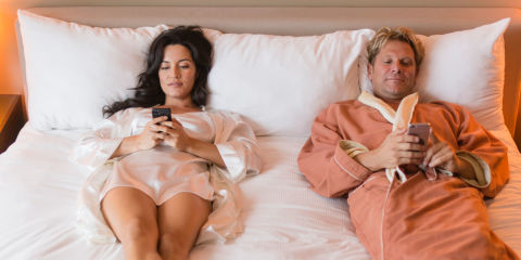 Couple in bed looking at cell phones
